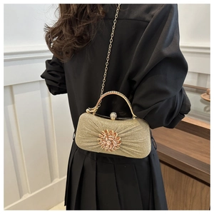 Détail d'une pochette de soirée dorée champagne avec tissu plissé et boucle fleurie en strass