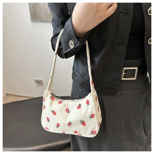 Détail du sac sous le bras en velours blanc avec imprimé fraise rouge et fermeture éclair