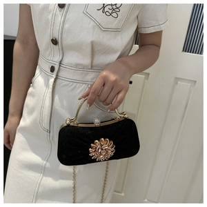 Détail de la pochette de soirée noire avec fleur en strass et chaîne dorée