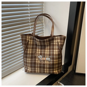 Detail of checkered tote bag featuring an embroidered dachshund and brown handles