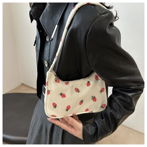 Détail du sac baguette en velours côtelé crème à motif fraises sur veste en cuir noir