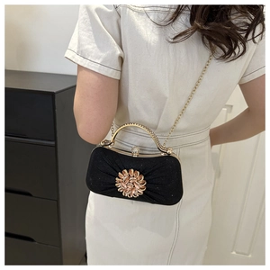 Détail de la pochette de soirée plissée noire avec boucle fleur en strass et anse dorée