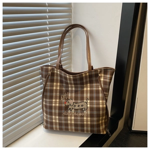 Detail of plaid tote bag featuring dachshund embroidery and brown handles on window sill