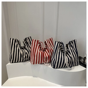 Detailed macro view of large canvas tote bags in black, red, and navy stripes on a white step