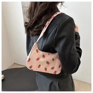 Gros plan d'un sac en velours côtelé à motif fraise porté par un mannequin en cuir