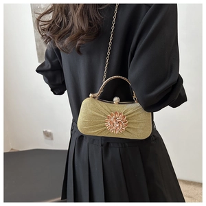 Détail d'une pochette dorée à paillettes avec grande fleur en gemmes et fermoir strass
