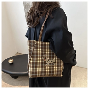 Detail of checkered tote bag featuring cartoon dachshund embroidery and leather handle