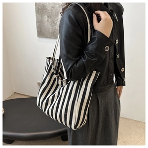 Detail of large striped canvas tote bag showing fit and capacity on female model