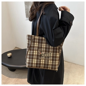 Detail of plaid tote bag featuring cartoon dachshund embroidery and leather strap