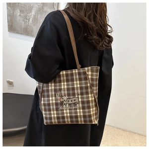 Close-up of brown plaid tote bag with cute dog embroidery and textual detailing