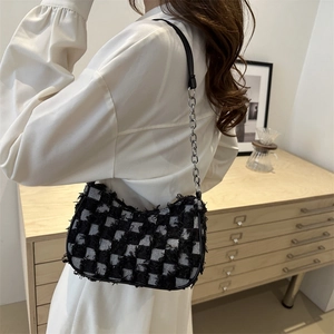 Women's black and white checkered denim underarm bag with fringe details and chain strap