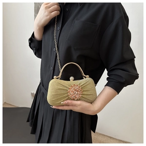 Détail d'une pochette dorée plissée avec strass en fleur et fermoir perle luxe