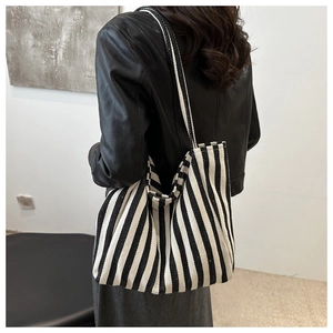 Detail of a large capacity striped canvas tote bag showing thick textured fabric and straps