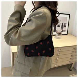 Détail d'un sac sous le bras en velours côtelé noir à imprimé fraises sur modèle