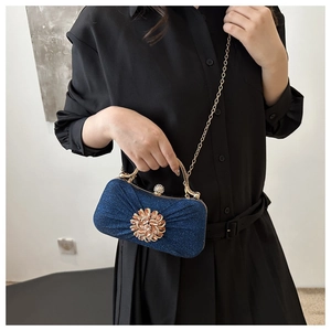 Détail d'une pochette de soirée pailletée bleu marine avec fleur en strass et bandoulière