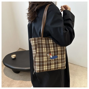 Close-up of vintage brown plaid tote bag featuring embroidered dachshund and long leather straps