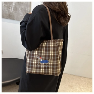 Detailed embroidery of a dachshund on a checkered canvas tote bag with leather strap