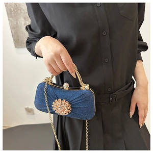 Détail de pochette de soirée pailletée bleu marine avec fermoir fleur strass et chaîne dorée