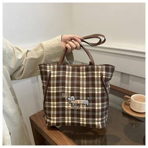 Detail of checkered tote bag featuring brown embroidery and versatile leather straps