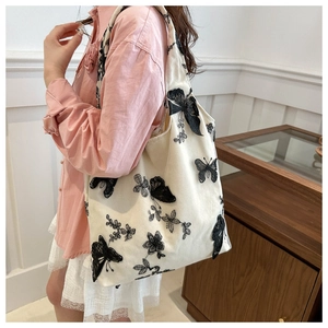 Detailed embroidery of black butterflies and flowers on a white canvas tote bag