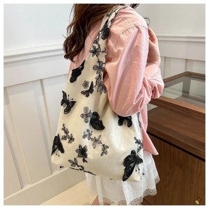 Off-white canvas tote bag with butterfly embroidery for women on pink shirt model