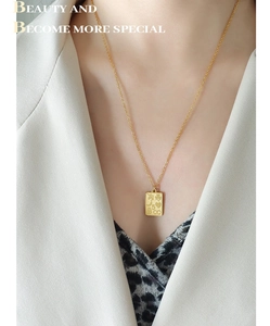 Gros plan détaillé d'un collier pendentif carré doré avec des symboles en relief mat