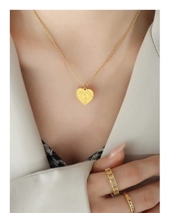 Gros plan d'un collier coeur doré avec gravure lapin et bagues assorties sur le mannequin
