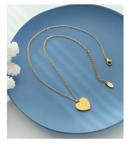 Détail du pendentif cœur doré avec gravure Oui/Non et poinçon K18 sur le fermoir