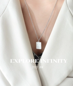 Détail du collier pendentif reine en argent avec plaque gravée sur mannequin en blazer