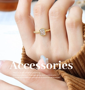 Detail of beaded gold band ring with a rectangular clear zircon stone on a model's hand