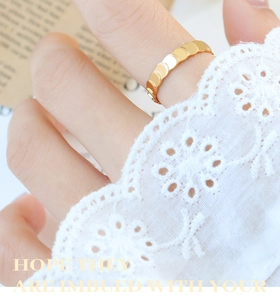 Detail shot of a gold-plated textured scale ring on a model with elegant lace cuff