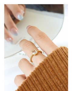 Detail of a gold-plated beaded ring featuring a rectangular zircon on a model's finger