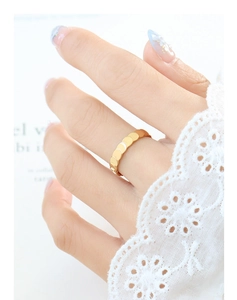 Close-up of golden scale-textured ring on finger with lace sleeve and blue nails