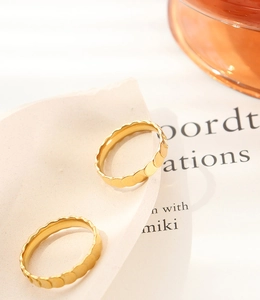 Macro detail of gold-plated titanium rings with unique scale texture and wavy edges