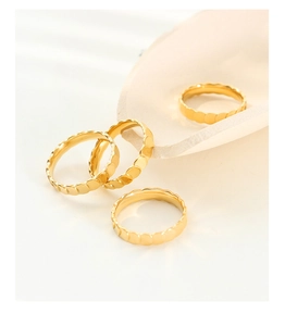Macro detail of gold-plated titanium steel rings with textured scale patterns on stone tray