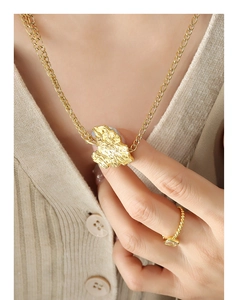 Primer plano de collar de hoja dorada y conjunto de anillo sobre punto beige