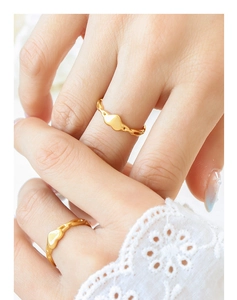 Gros plan d'une bague coeur dorée avec un anneau à texture de chaîne tressée élégant