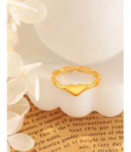 Détail d'une bague coeur dorée évidée en chaîne sur un élégant décor floral