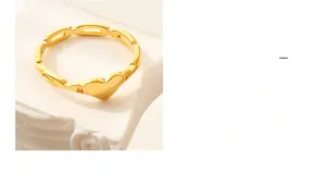 Macro d'une bague coeur dorée évidée avec anneau en chaîne sur socle blanc élégant