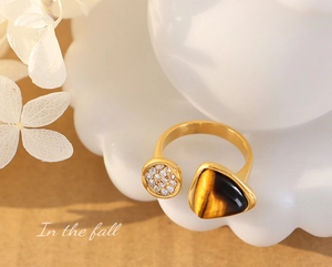 Close-up of gold titanium ring with tiger eye stone and zircon in autumn setting