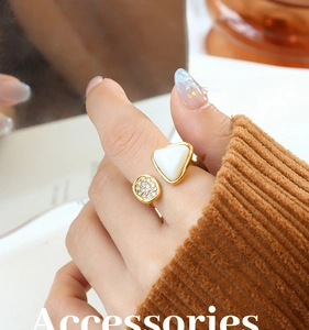 Close-up of gold open ring with triangular shell inlay and pavé disk on model finger