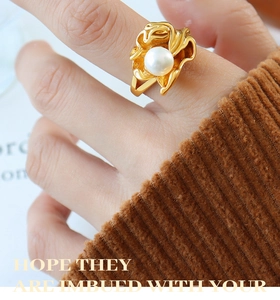 Macro shot of irregular gold wavy ring with a white freshwater pearl on knit background