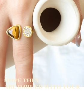 Detailed close-up of a gold ring featuring tiger eye stone and micro-set cubic zirconia