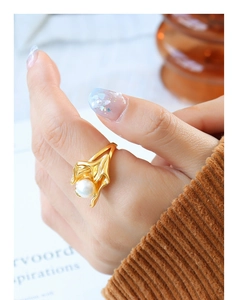 Detailed view of irregular gold petal ring with a lustrous white pearl on a finger