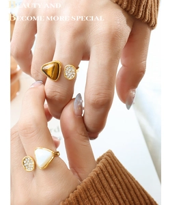 Detailed view of French vintage tiger eye and shell rings with zircons on hand