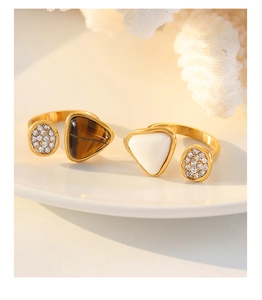 Detail of adjustable gold-plated rings featuring tiger eye and zircon inlay on ceramic base