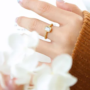 Vintage style gold beaded ring with a rectangular cubic zirconia on a model's hand