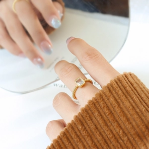 Gold geometric ring with rectangular zircon and beaded band on a model's finger