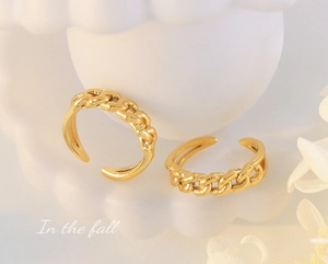 Close-up of two golden Cuban link chain rings with adjustable bands on white decor