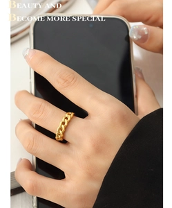 Detail showing a gold chain ring on a finger with a smooth polished metallic finish